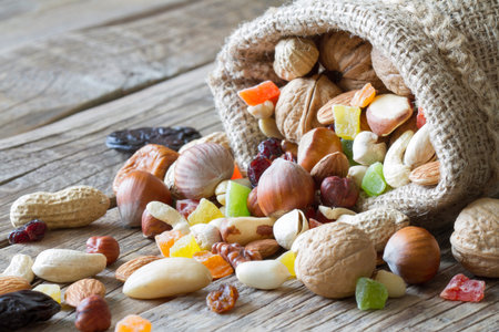Mix of dried fruit and nuts in jute sack on wooden backgroundの写真素材
