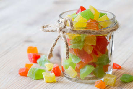 Candied fruits in glass jar on wooden backgroundの写真素材