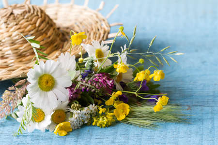 Field flowers under straw hat on blue planks, summer conceptの写真素材