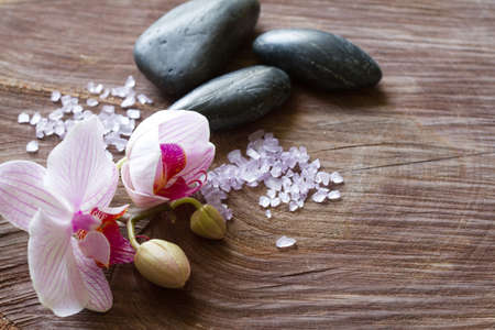 Bath salt, orchid and massage stones on wooden background, spa conceptの写真素材