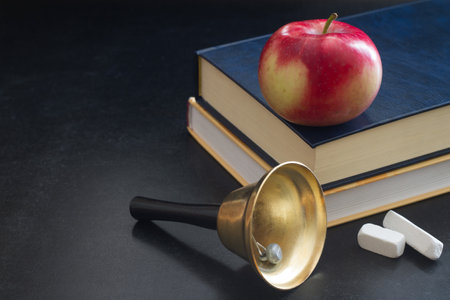 Bell, books and apple on blackboard, back to school conceptの写真素材