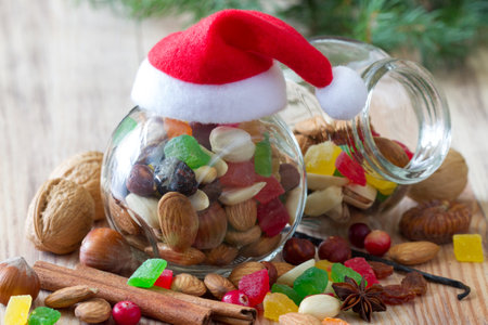 Christmas mix of nuts and dried fruit in glass jar with santa hat, christmas food conceptの写真素材