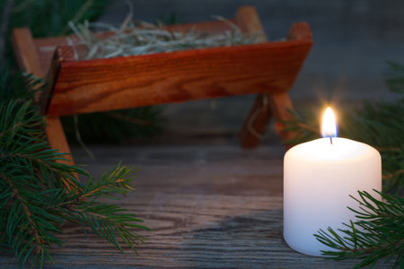 Burning candle and christmas manger in background, prayer and waiting for coming of Jesus conceptの写真素材
