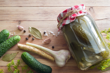 Homemade pickled cucumbers with dill, garlic, horseradish and spices in glass jar on wooden backgroundの写真素材