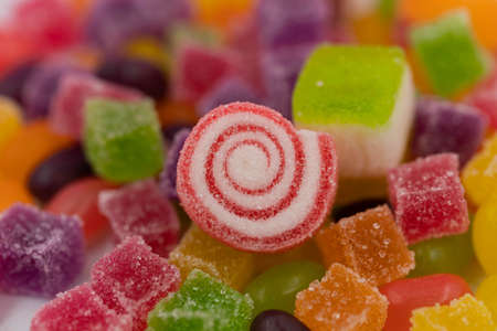 Closed up three spiral shape jelly candy, yellow red orange roll with sugar surface, pastel bright pink backgroundの写真素材
