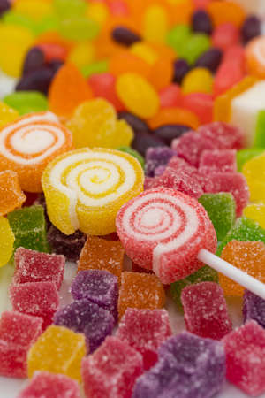 Closed up three spiral shape jelly candy, yellow red orange roll with sugar surface, pastel bright pink backgroundの写真素材