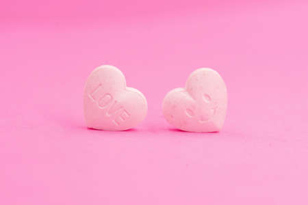 Couple of pink heart candy, Closed up love wording and smiley face for lovely celebration, sweetie pastel valentine backgroundの写真素材