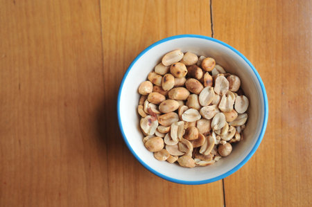 A bowl of roast peanuts on a wooden table