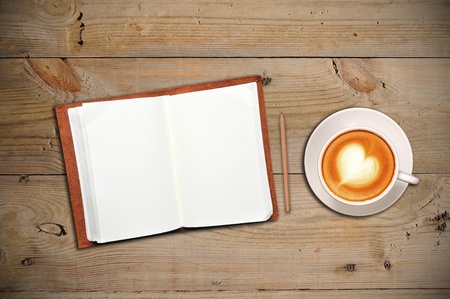 Open notebook with cup of coffee on a wooden floorの写真素材