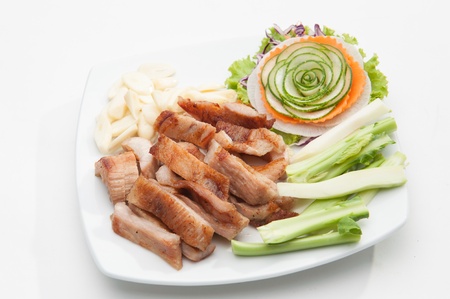 Fried pork served with various vegetables on white dish の写真素材