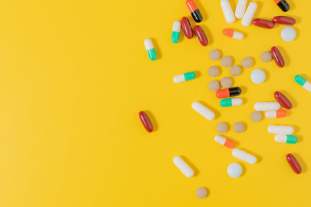 Image of tablets and capsules with medicine of different colors on a yellow background