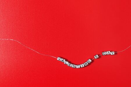 The inscription Valentine's day laid out in small letters on a ribbon on a red backgroundの写真素材