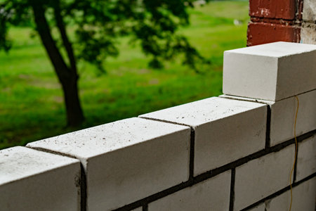 Worker puts a white brick on a construction site