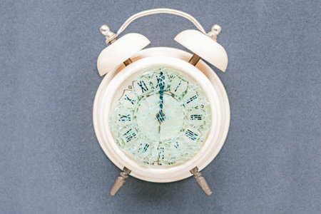 View of an old alarm clock in light beige on a dark background