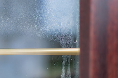 A fragment of a window made of laminated PVC profile fogged from the inside