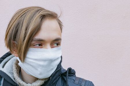 An adult guy puts a protective medical mask on his faceの写真素材