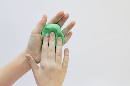 Children's hands play with a sticky mass of green colorの写真素材