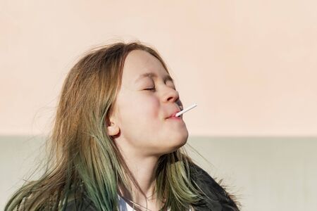 A young girl in a dark jacket poses in front of the cameraの写真素材