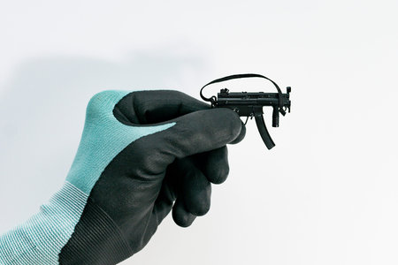 Image of a gloved hand and a toy machine on a light background