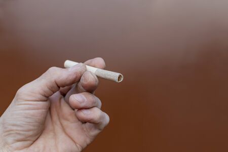 The hand of a working man holding an old cigaretteの写真素材
