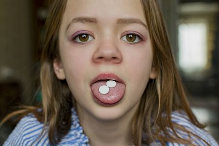 A young girl takes two pills for the diseaseの写真素材