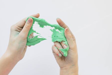 Children's hands play with a sticky mass of green colorの写真素材