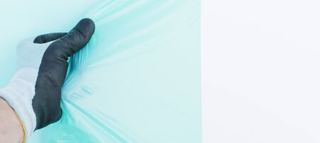 A gloved worker removes the film from the white plasticの写真素材