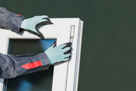 A worker in overalls collects a plastic window before installationの写真素材
