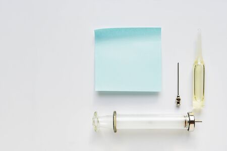 Sheet of paper, syringe, needle and ampoule on a light backgroundの写真素材