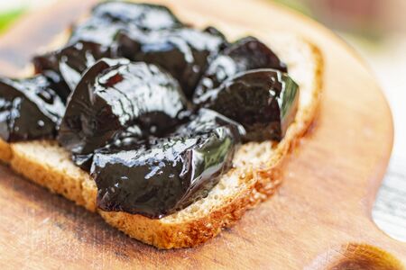Dark berry jam spread on a piece of black breadの写真素材