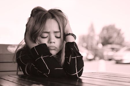 Tinted image of a young girl sitting at a table in a cafeの写真素材