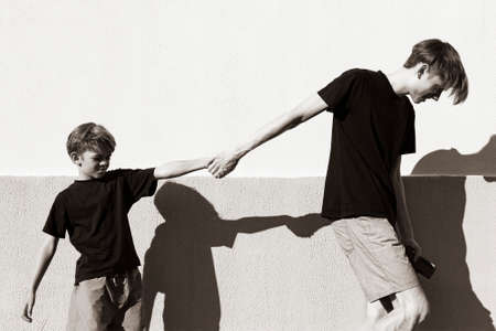 A small boy is playing with his older brother in the courtyard of the house. Black and white photoの写真素材