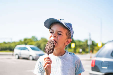 Little boy eating chocolate ice cream outside on a Sunny dayの写真素材