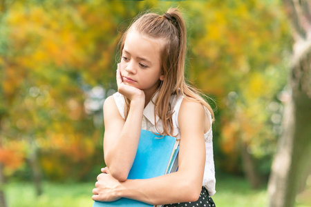 A young girl student in uniform holding textbooks