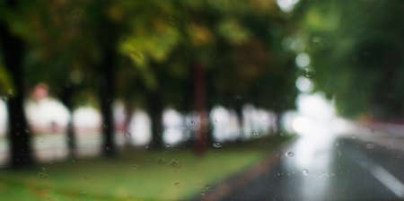 Blurry image through the car window. Autumn landscape of the city during the rainの写真素材