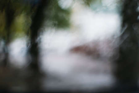 Blurry image through the car window. Autumn landscape of the city during the rainの写真素材