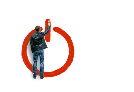 Conceptual collage a young guy draws a large sign with a brush to turn on the equipmentの写真素材