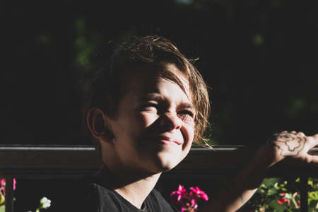 Portrait tinted image of a little boy on a balcony enjoying the sunset raysの写真素材