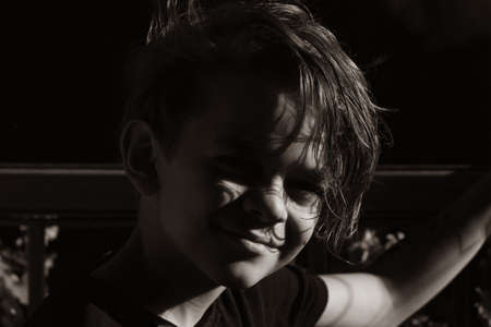 Portrait tinted image of a little boy on a balcony enjoying the sunset raysの写真素材