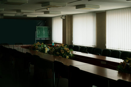 Large hall for sports meetings on football. Long tables and bouquets of flowers