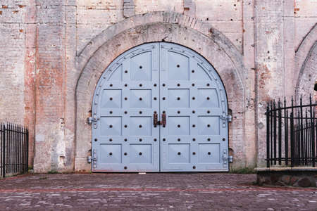 Large old metal and wood gates in an ancient maroon brick castleの写真素材