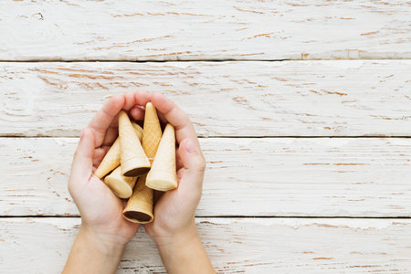 Hands of a little boy holding sweet cakes in his hands on a decorative backgroundの写真素材