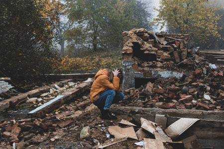 A young girl cries over a burned and destroyed private houseの写真素材