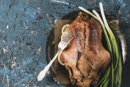 Tinted image of a baked duck on a plate with a fork on a decorative backgroundの写真素材