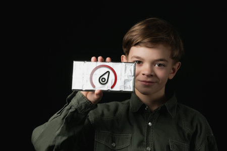 a little boy holds a chocolate bar in foil on a dark background