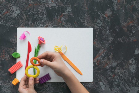 A little boy sculpts a gift for March 8 for his mother on a decorative table
