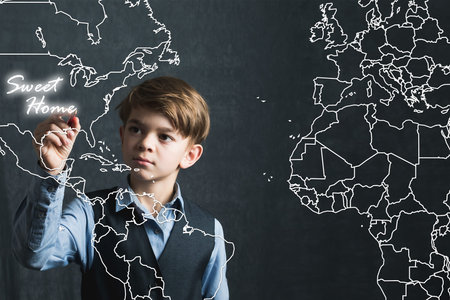 A little boy in uniform writes on an imaginary map of America
