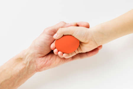 Hand of a child and an adult holding an Easter egg on a light backgroundの写真素材