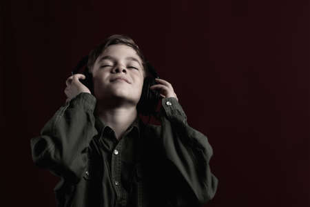 Tinted image of a little boy listening to music with headphones on his phoneの写真素材
