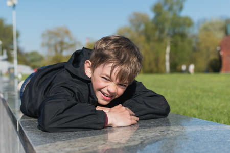 A little boy walks in a city park, walks on a granite parapetの写真素材